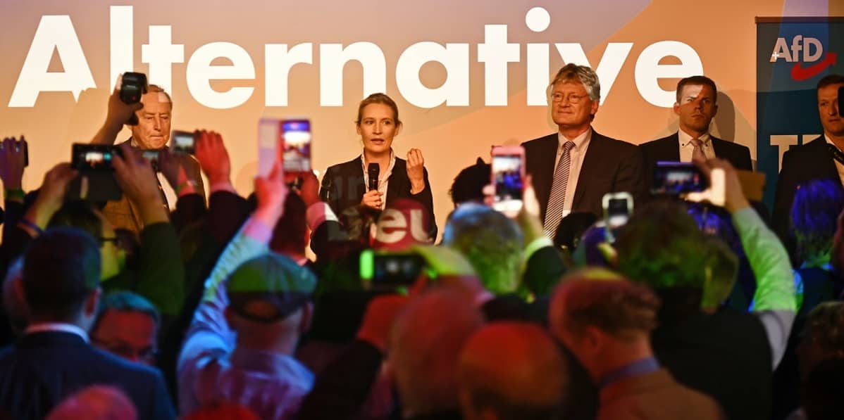 Kännykkäkamerat nostettu ilmaan kuvaamaan Alternative-tekstin edessä seisovia ihmisiä.