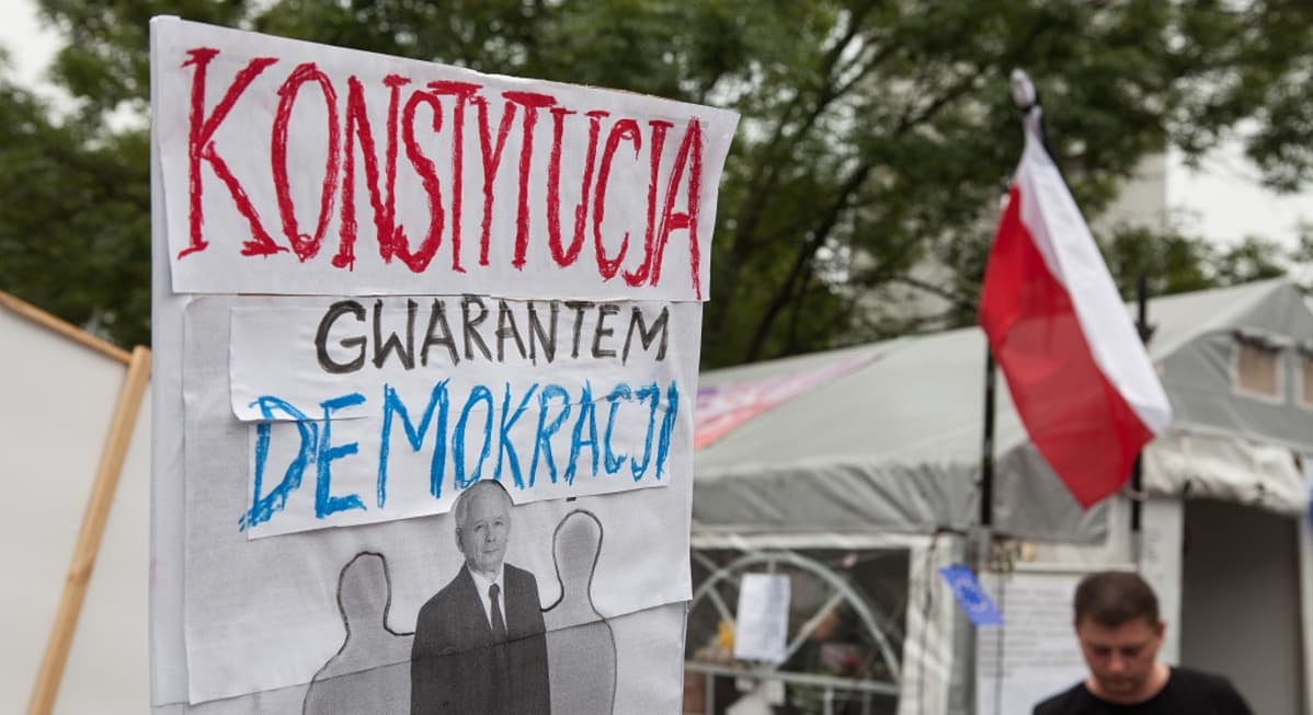Mielenosoittajien kyltti, jossa teksti: konstytucja gwarantem demokracji.