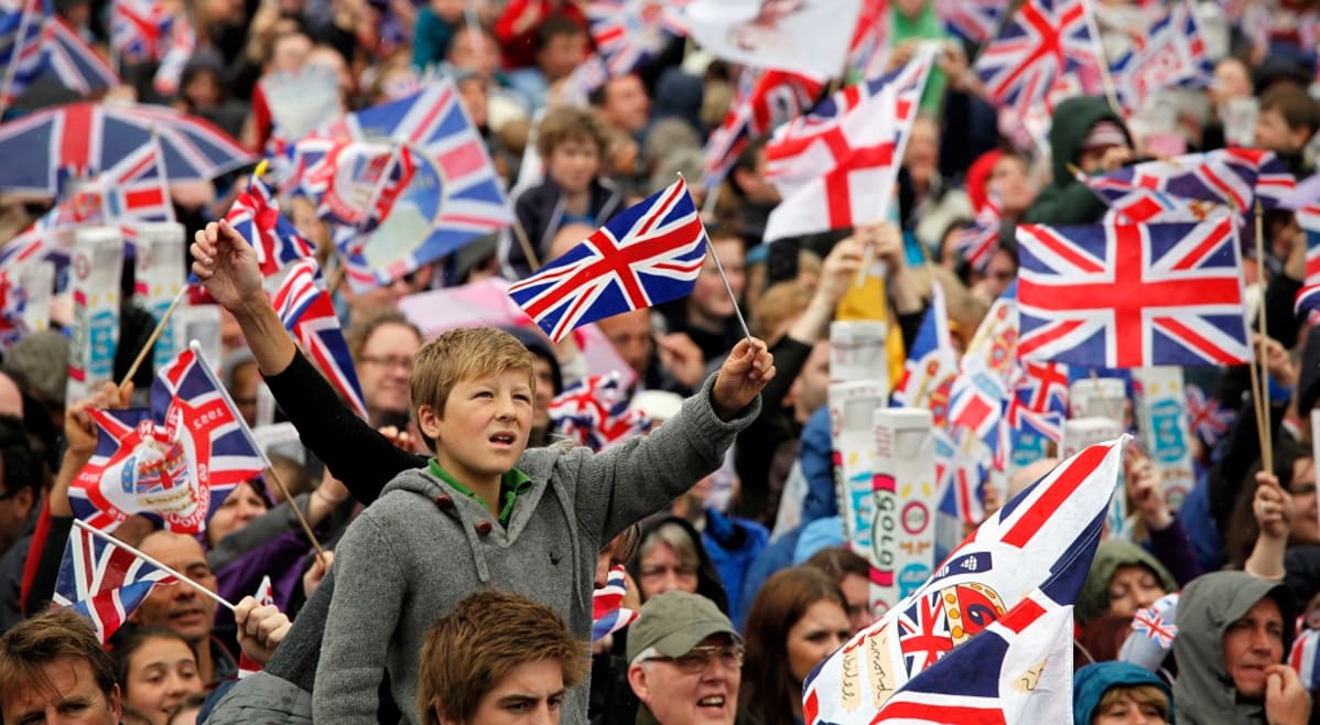 Suuri ihmisjoukko heiluttaa Britannian ja Eglannin lippuja.