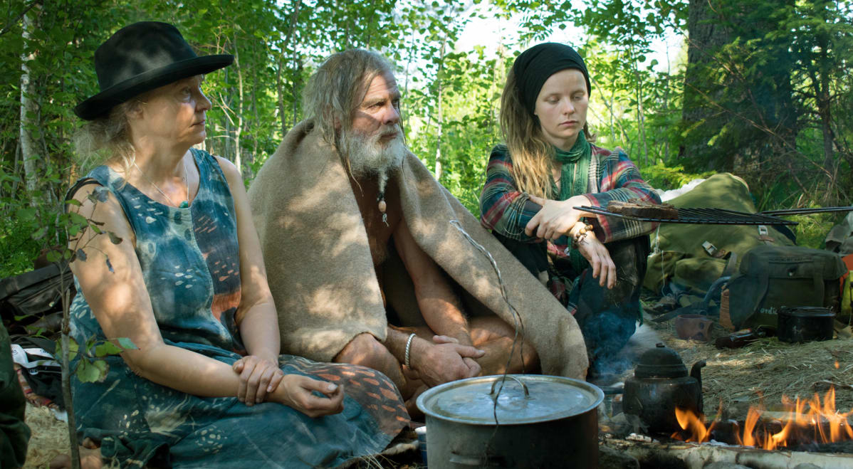 Ihmiset nuotion äärellä survivalistien leirillä Keski-Suomessa.