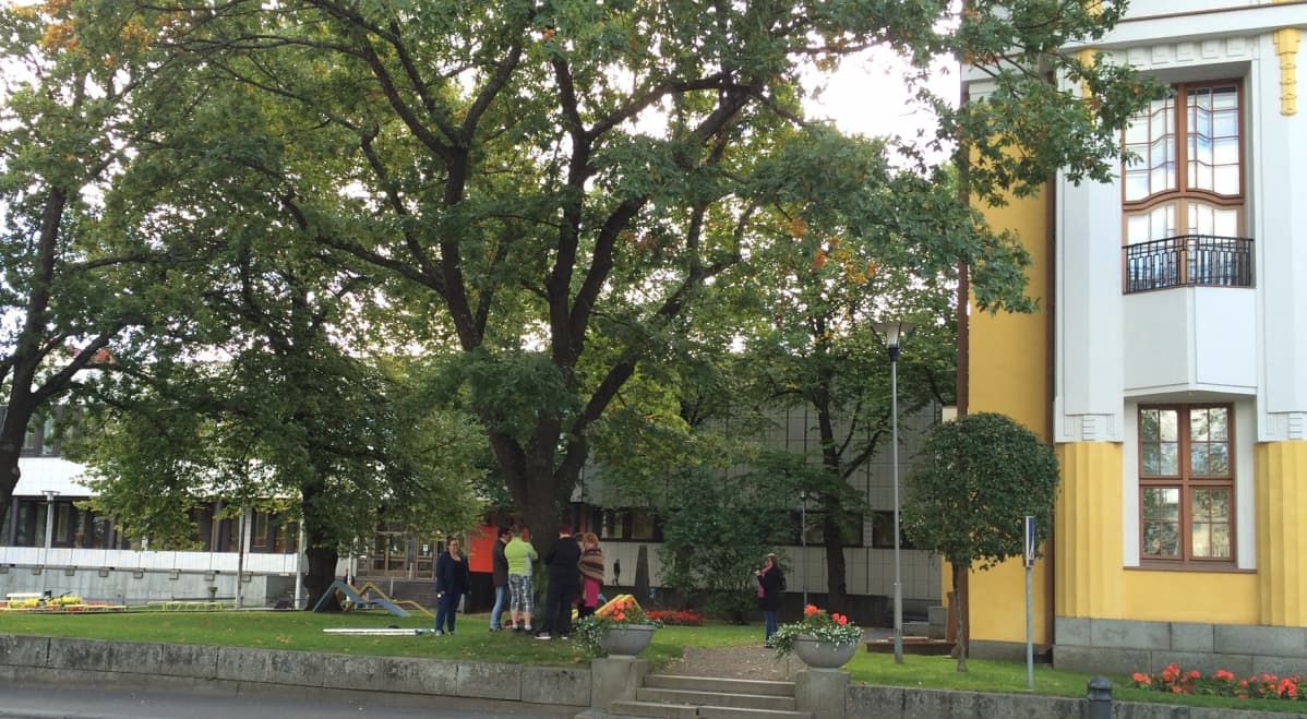 Ihmisiä koristelemassa puuta virkatuilla tilkuilla.