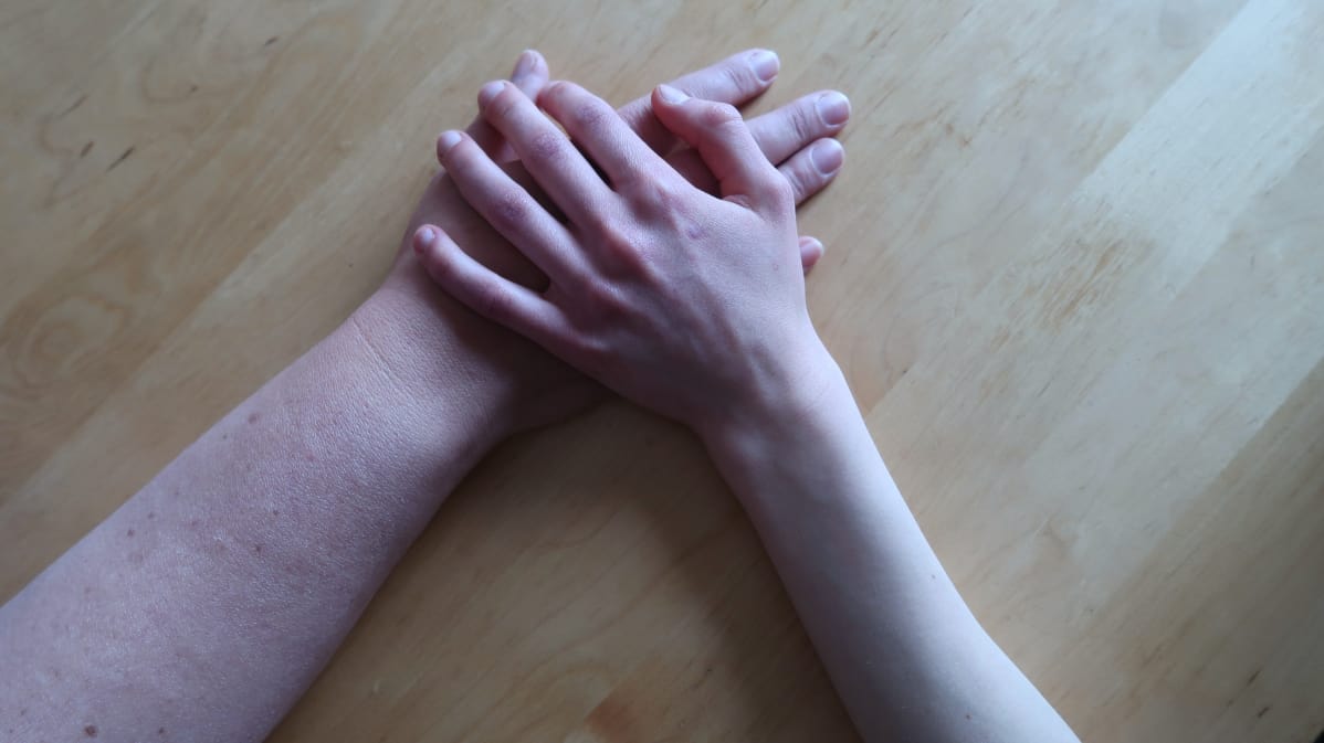 Lapsen laiha käsi äidin käden päällä