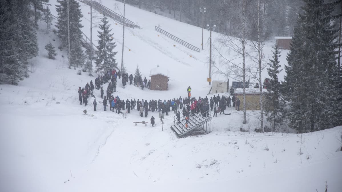 Ihmiset odottavat lumisateessa