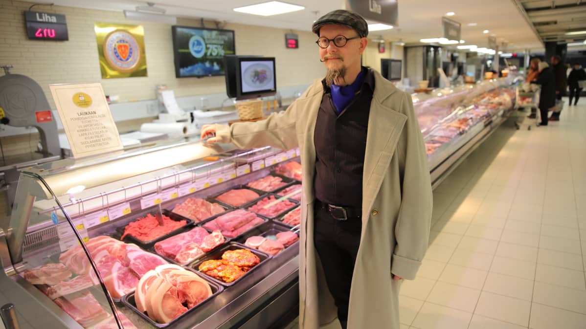 Kansallispuvun takkiin pukeutunut mies lihatiskillä