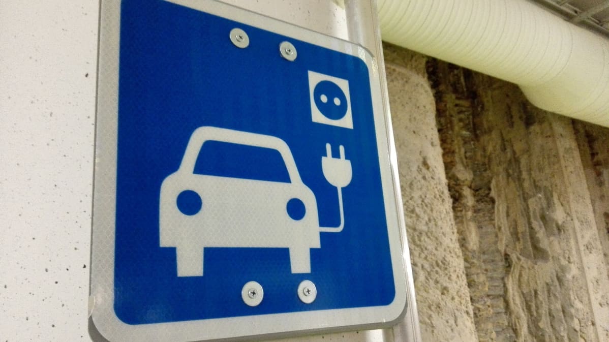 Sähköauton latauspisteen merkki parkkihallissa.