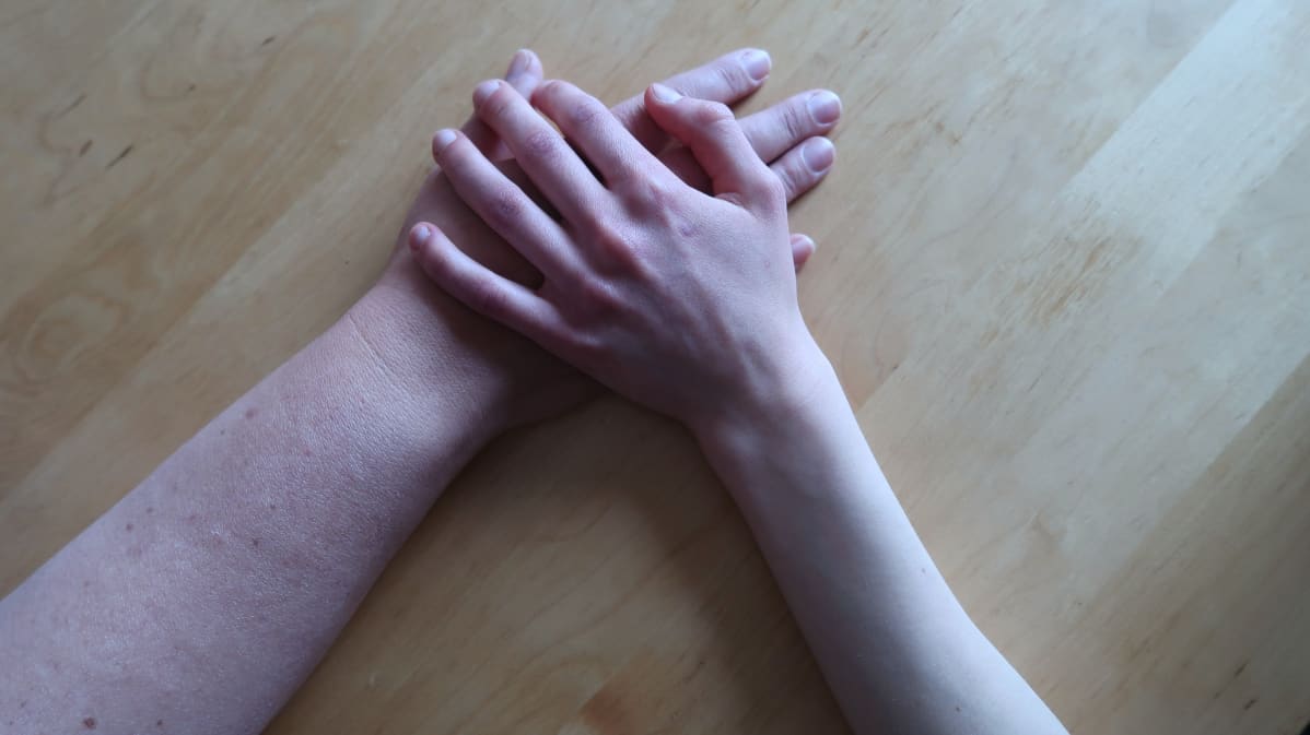 Lapsen laiha käsi äidin käden päällä