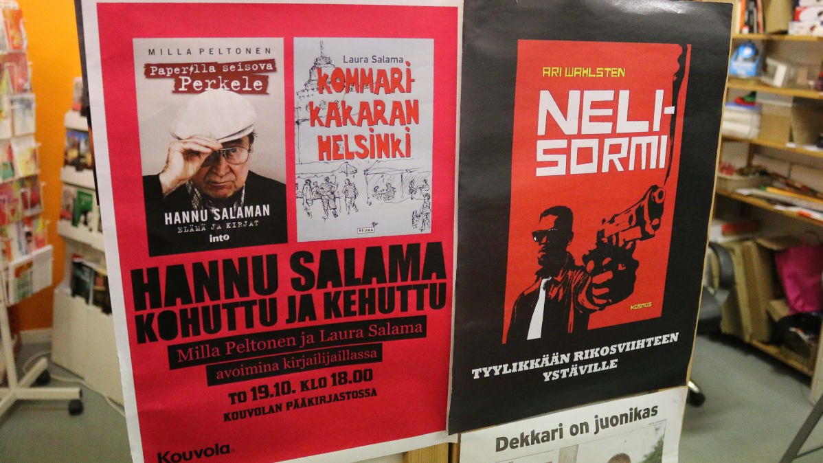 kirja ja kirjailijajulisteita kirjakyllyn päädyssä, julisteissa Hannu Salama ja Ari Wahlsten