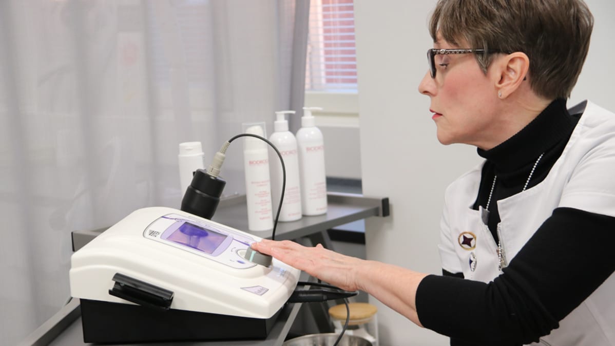 Kauneudenhoitoalan lehtori Outi Tukki säätää radiofrekvenssilaitetta