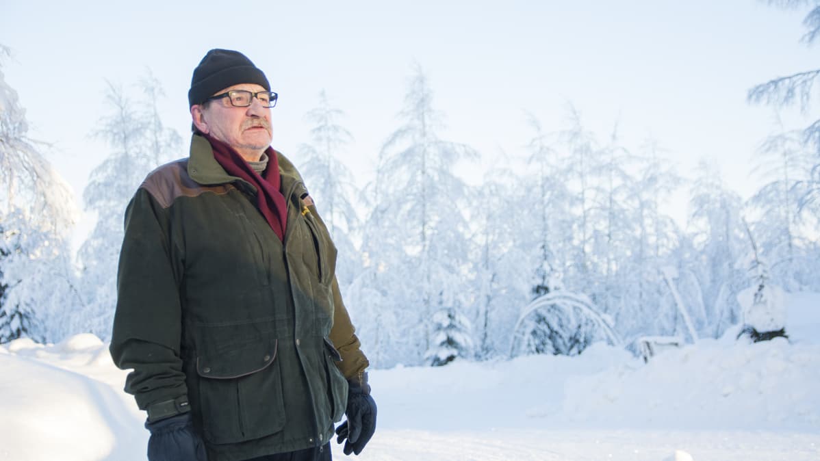 Mies seisoo pakkasessa tien varressa.
