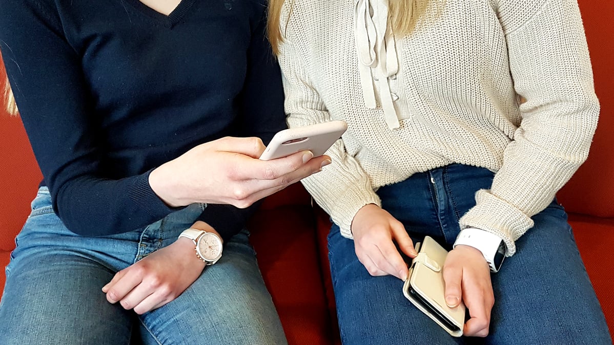 Kaksi tyttöä viestittelee puhelimella.
