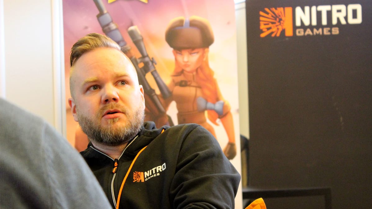 NitoGames pelifirman toimitusjohtaja Jussi Tähtinen istuu työpaikallaan, taustalla yrityksen roll-up