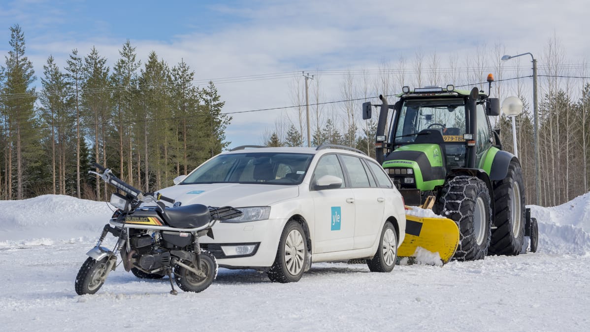 Mopo, henkilöauto ja traktori parkkialueella.