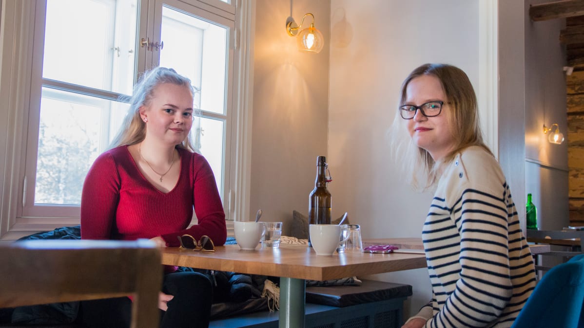 Kaksi nuorta naista istuu ravintolapöydän ääressä.