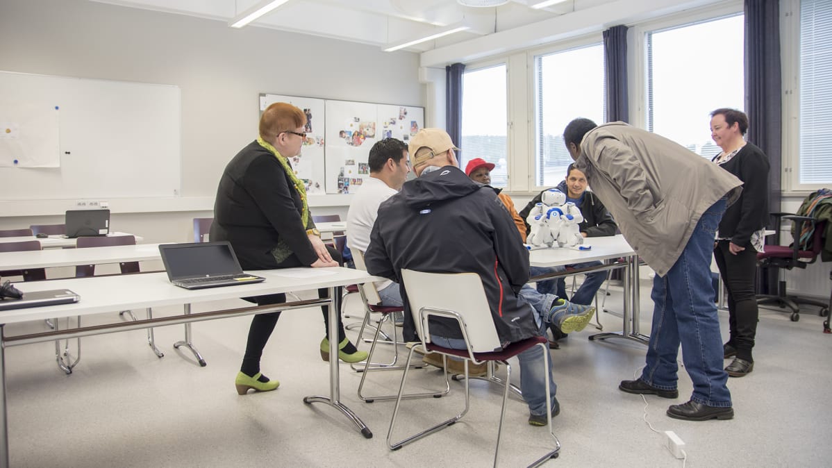 Opiskelijat ja opettajat ovat humanoidirobitin ympärillä luokkahuoneessa.