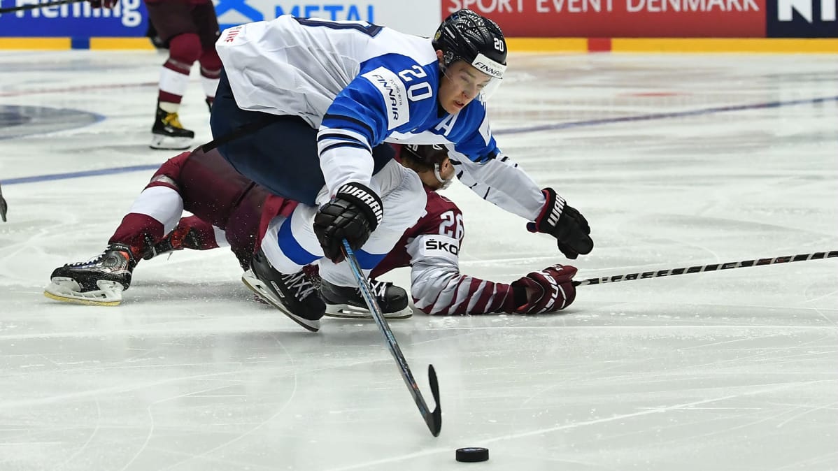 Leijonien Sebastian Aho taistelee kiekosta Latvian Uvis Baliskisin kanssa.