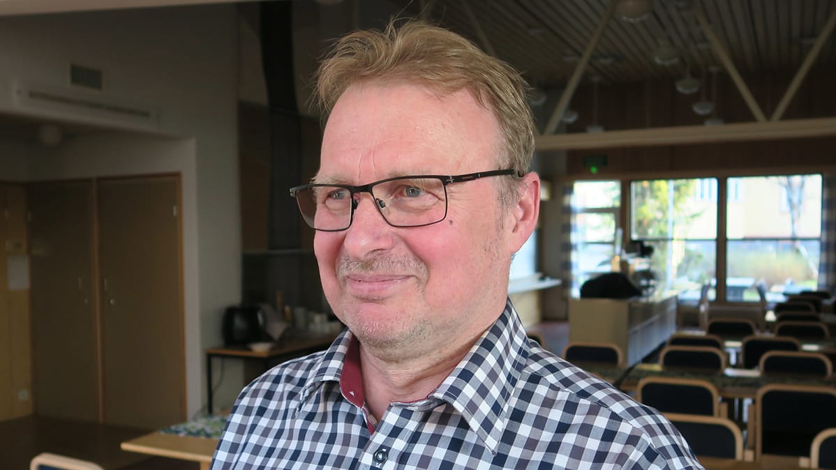 Silmälasipäinen mies poseeraa kameralle