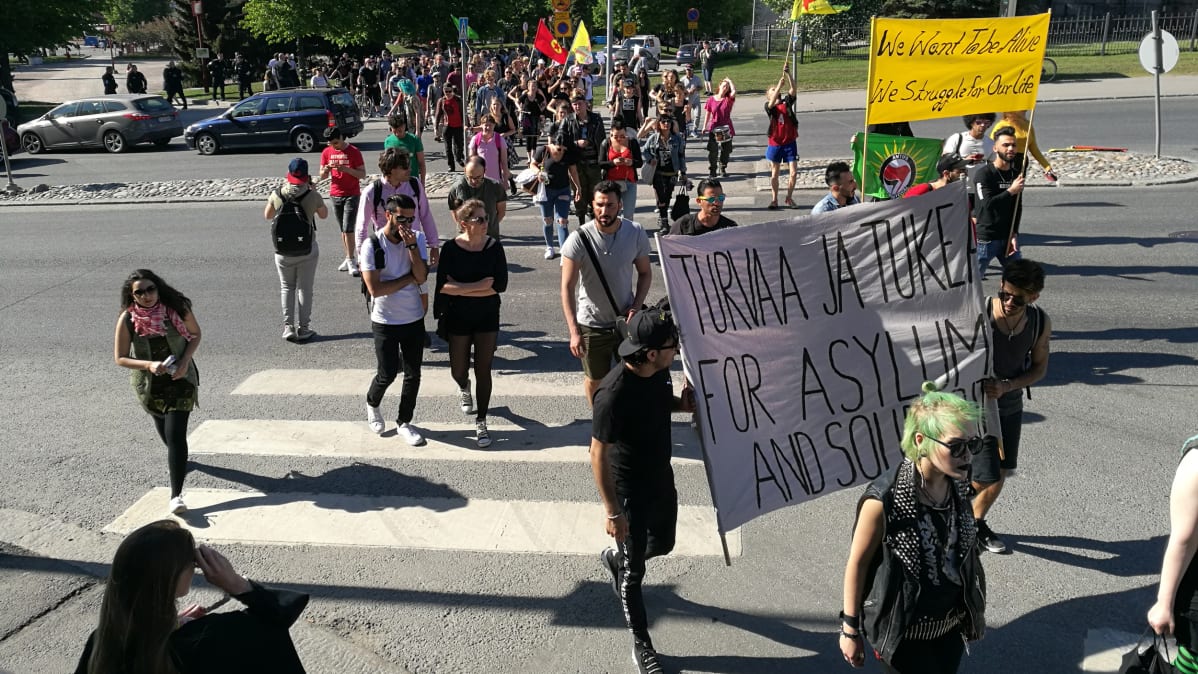 Mielenosoittajat ylittämässä katua banderollien kanssa