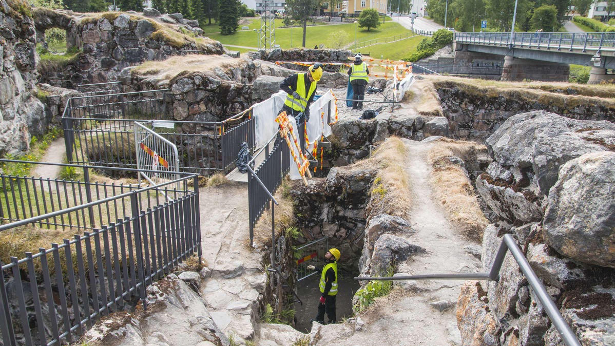 Konservaattori ja restaurointiapulaiset ovat työskentelemässä muinaismuistokohteessa.