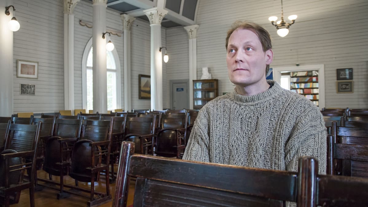 Pekka Ervast -temppelin entinen vahtimestari Sampsa Kuukasjärvi istuu penkillä.
