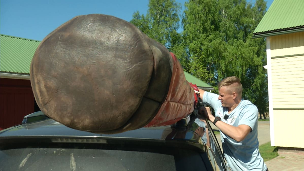 Elmo Savola kiinnittää seipäitään autonsa katolle.