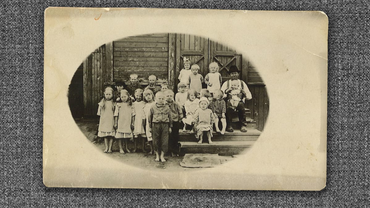 Mustavalkoinen kuva 1920-luvulta, 20 lasta rakennuksen portailla.