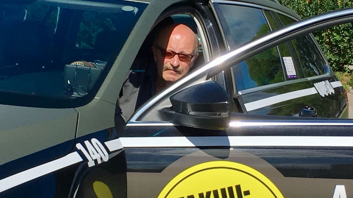 Kajaanin taksiautoilijoiden puheenjohtaja Erkki Korhonen istuu taksinsa kyydissä.