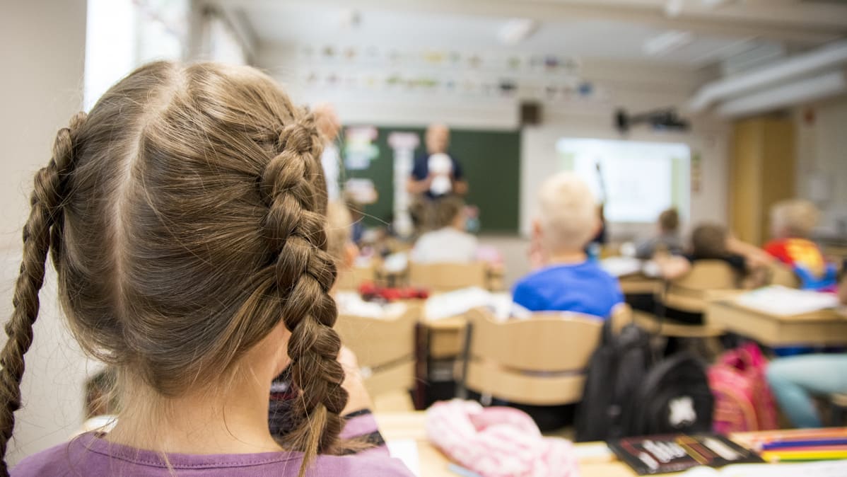 Lettipäinen tyttö takaapäin kuvattuna oppitunnilla.