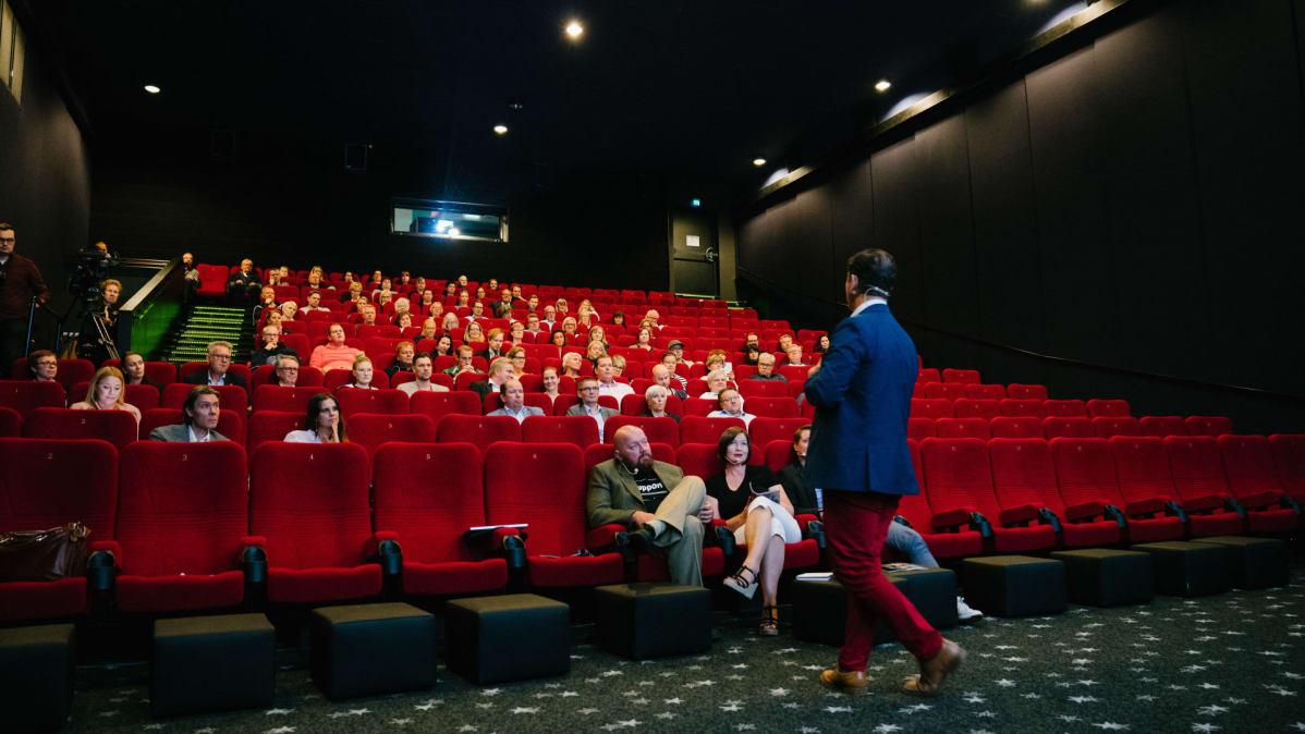 Speakersforumin André Noël Chaker rohkaisee yleisöä ennen elokuvaa voittamaan puhumisenpelkonsa.