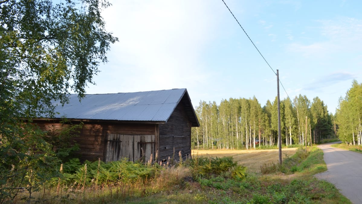 Huonokuntoinen lato kapean asfaltoidun tien varressa, pellon laidalla Virolahdella.