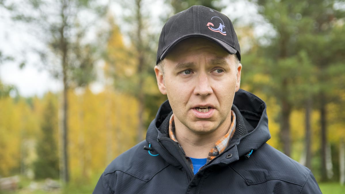 Lippalakkipäinen mies syksyisessä kuvassa