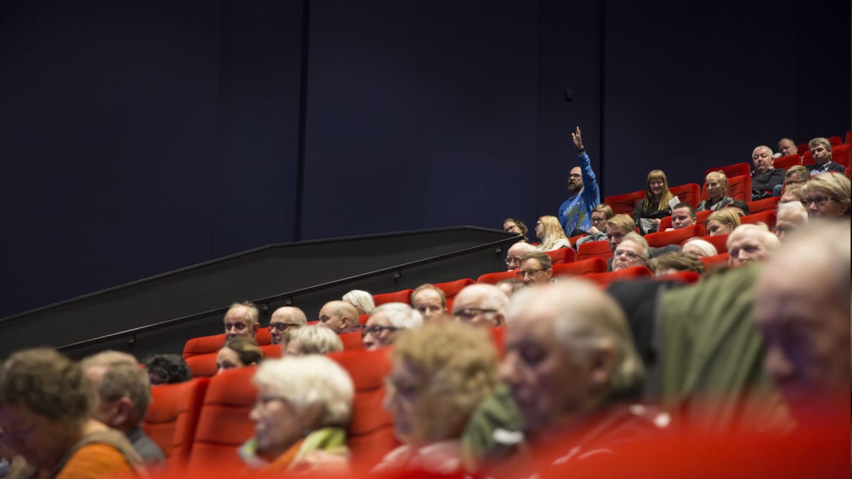 Mies viittaa yleisössä Finnpulpin tiedotustilaisuudessa.