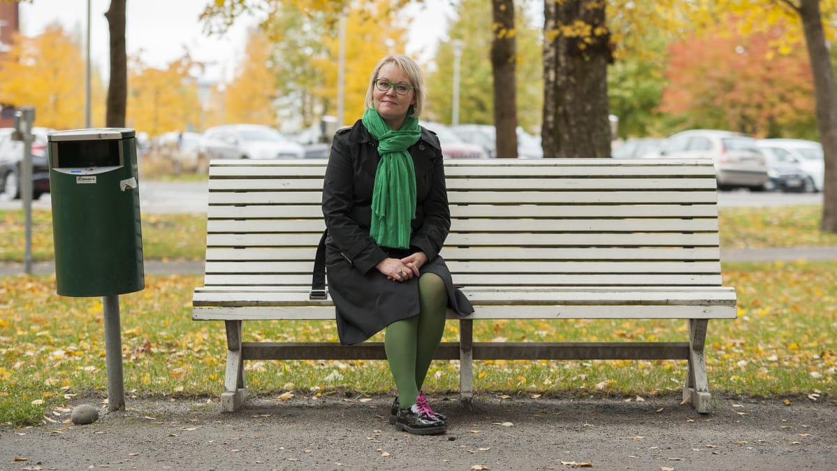 Riitta Salke istuu puistonpenkillä Kuopion kasarmialueella.