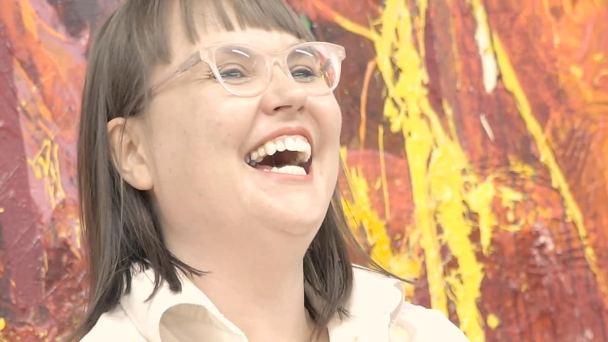 Maaria OIkarinen nauraa maalatessaan.
