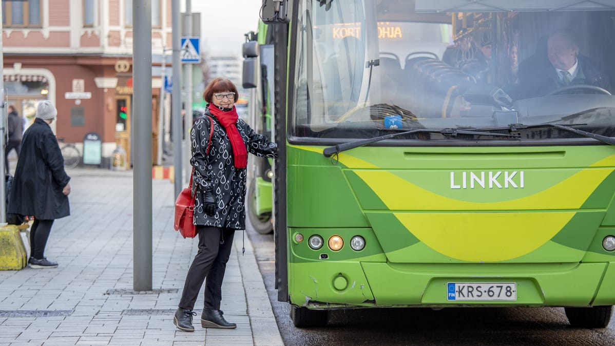 Nainen on astumassa linja-autoon.