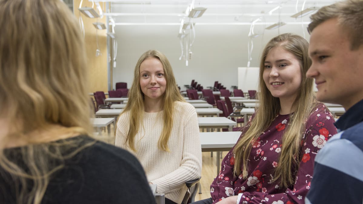 Nuoret istuvat pöydän ääressä keskustelemassa.