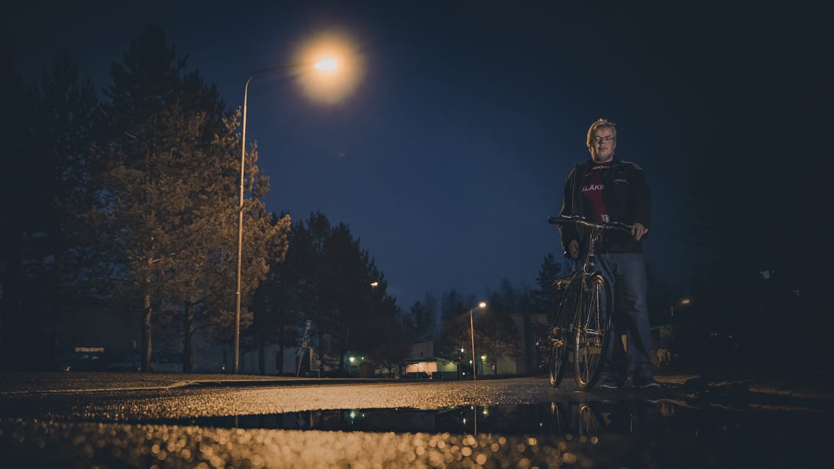 Konsta Pylkkänen taluttaa polkupyörää katuvalojen loisteessa.