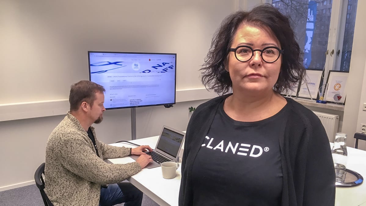 nainen ja taustalla mies tietokoneella