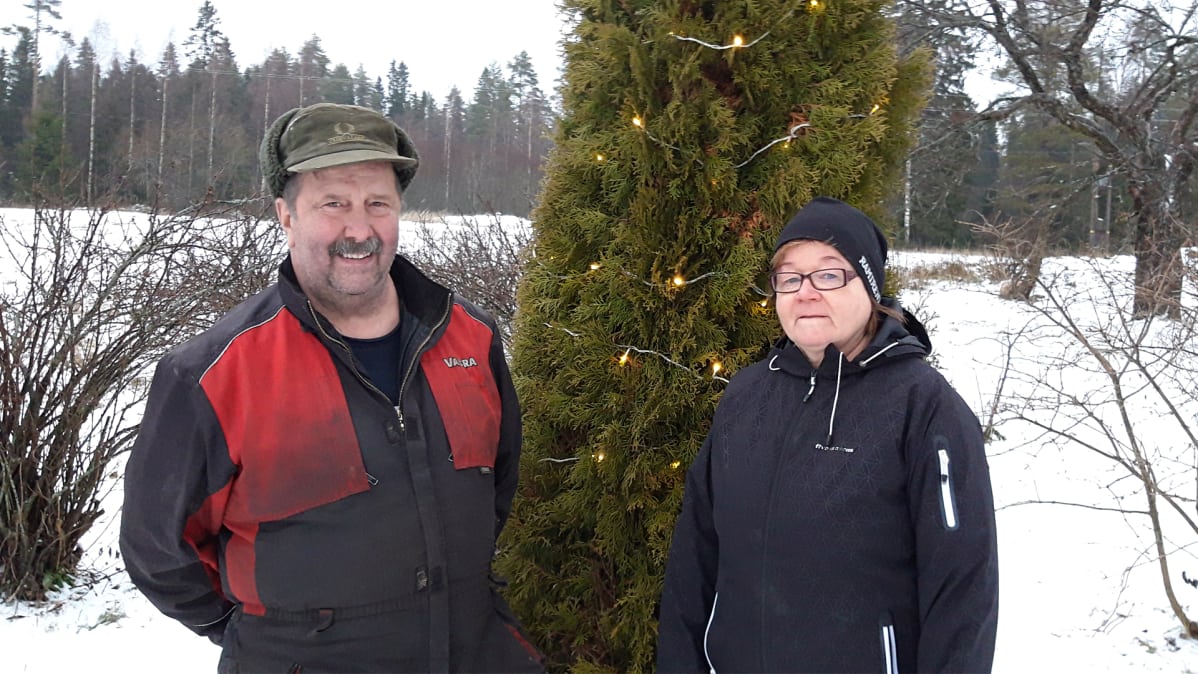 Pertti ja Leila Hujanen seisovat maatilan pihamaalla.