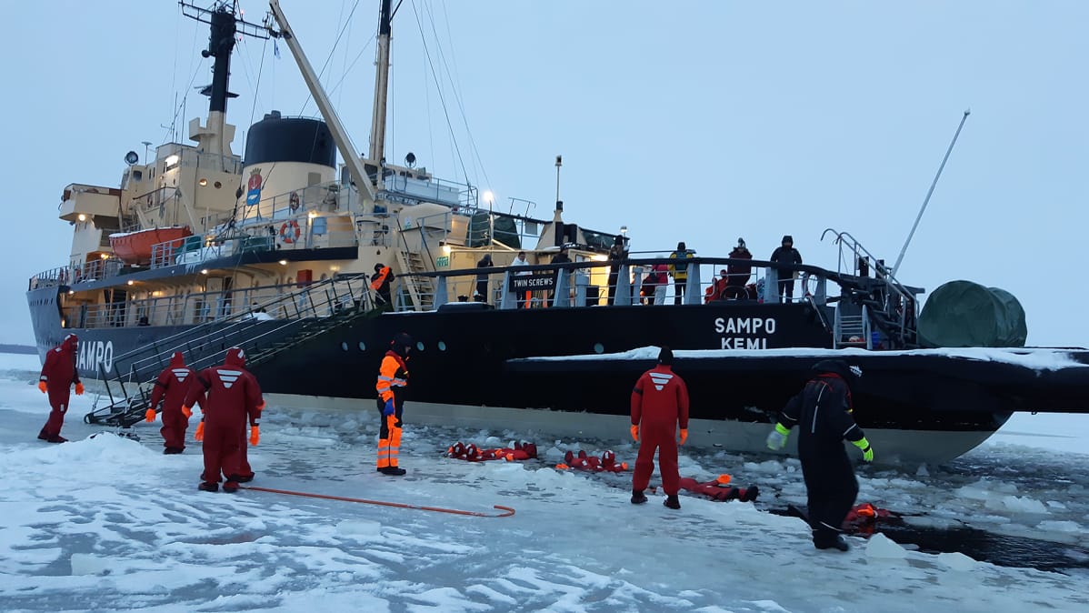 Jäänmurtaja Sampo pysähdyksissä Perämerellä kun turistit kelluvat meressä.