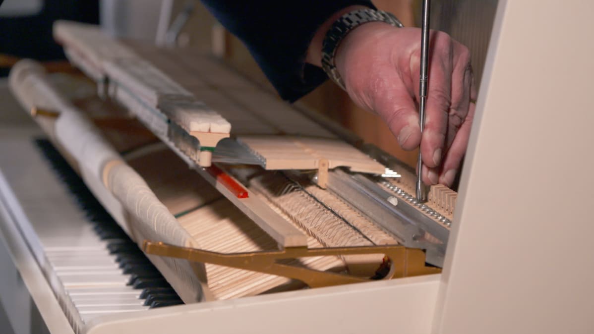 Pianonvirittäjä Pekka Savolainen huoltaa pianoa.
