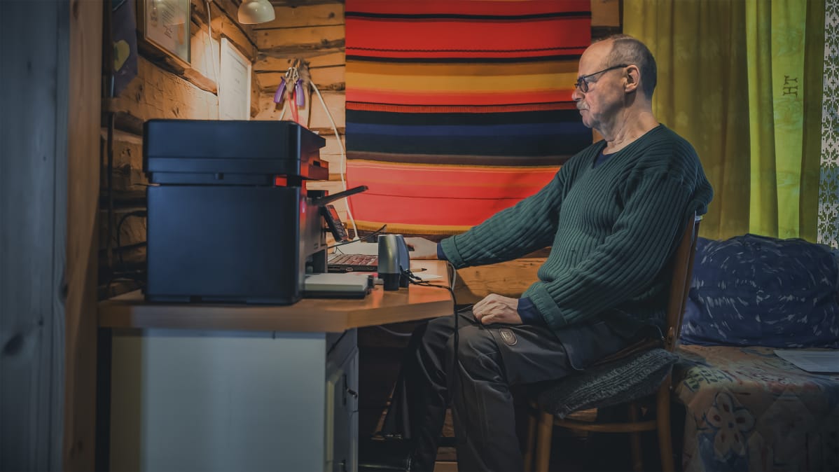 Mies istuu tietokoneella