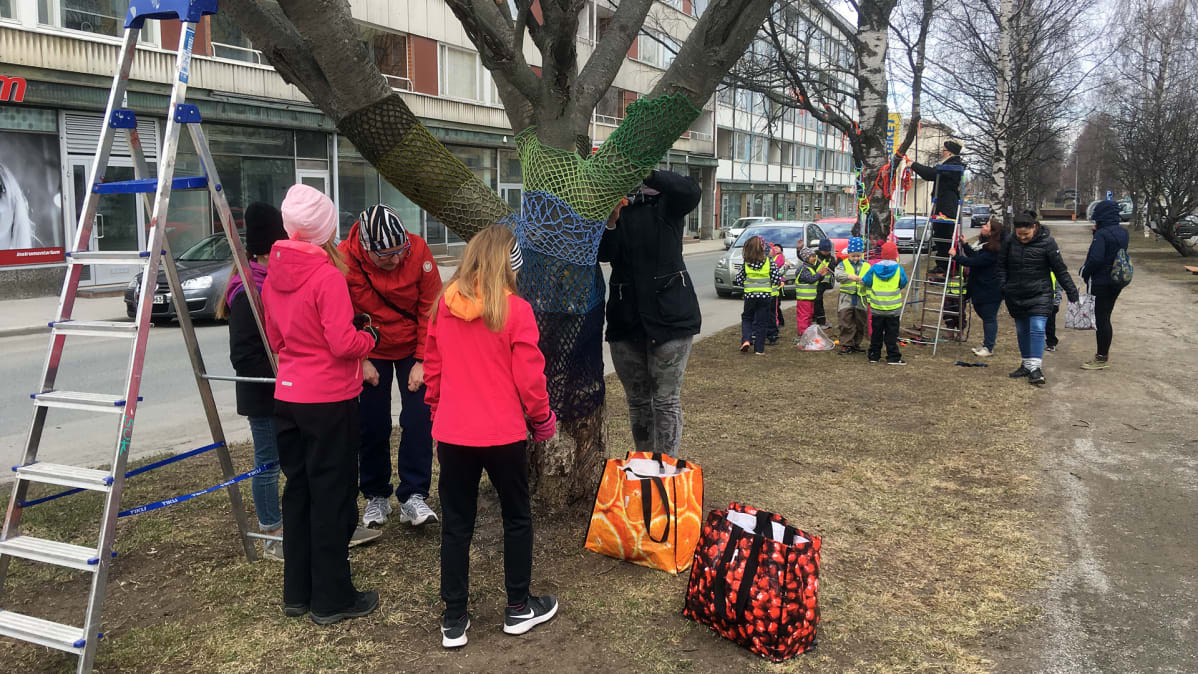 Koululaiset ja esikoululaiset koristelevat puistokadun puita Kemissä.