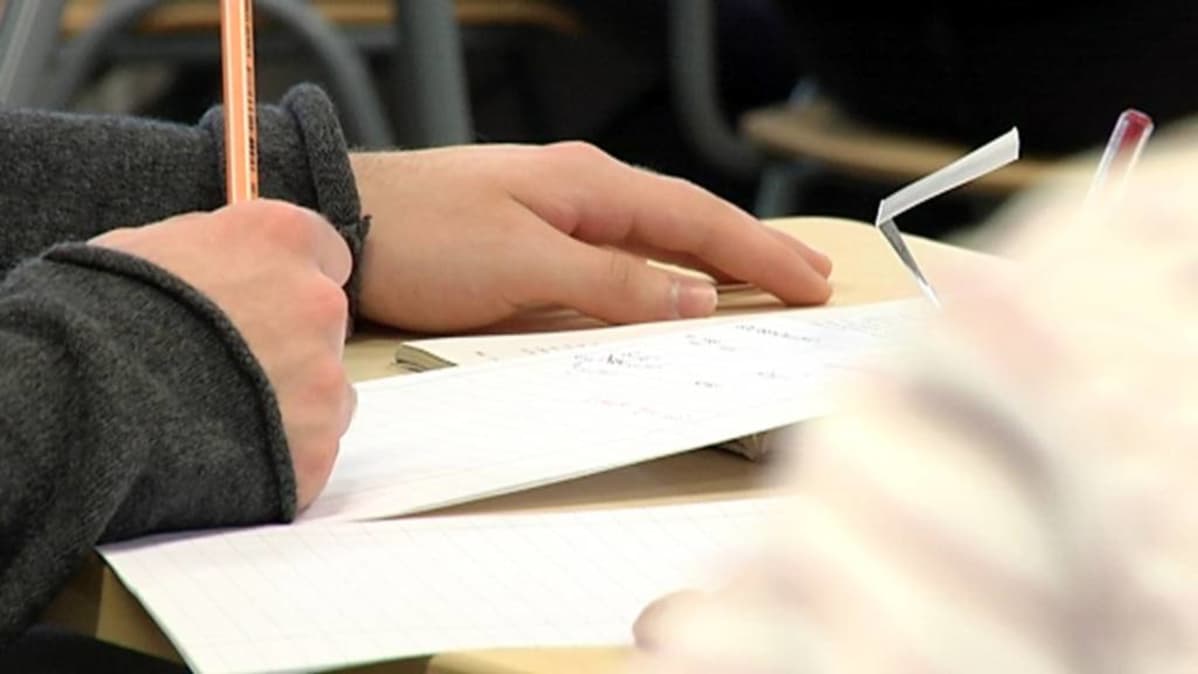 Opiskelija kirjoittaa muistiinpanoja.