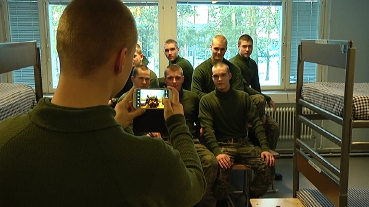 Varusmies ottaa kuvia tovereistaan tuvassa.