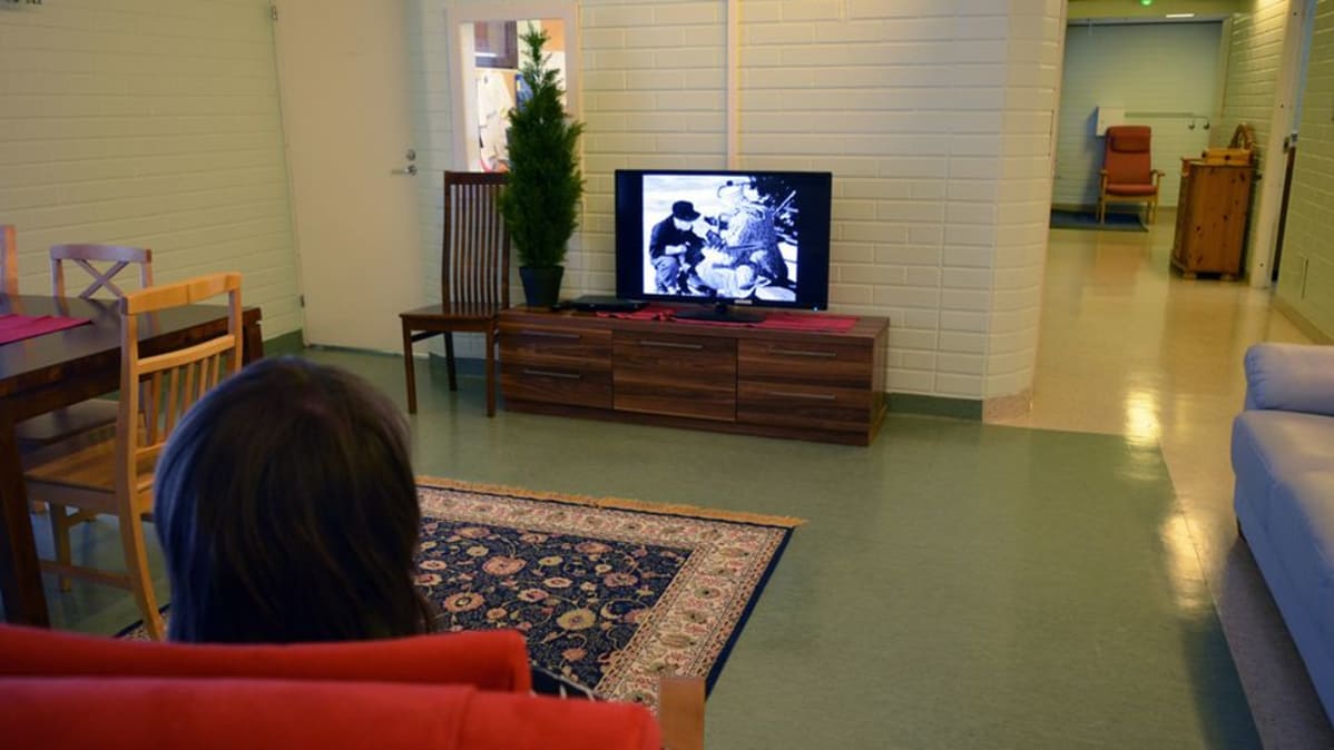 Kehitysvammainen asukas katselee televisiota kajaanilaisessa laitoskodissa.