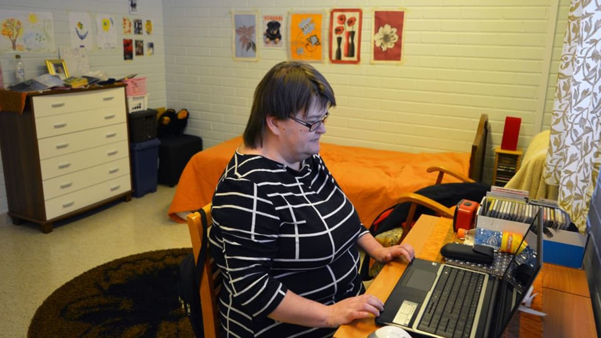 Mia Korhonen istuu palvelukeskuksessa omassa huoneessaan, pöydän ääressä tietokoneella.