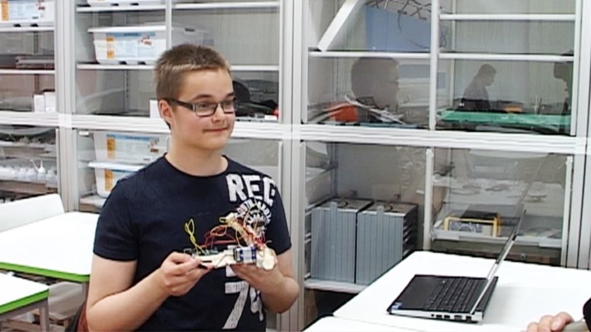 Nuori mies elektroniikkalaite käsissään.