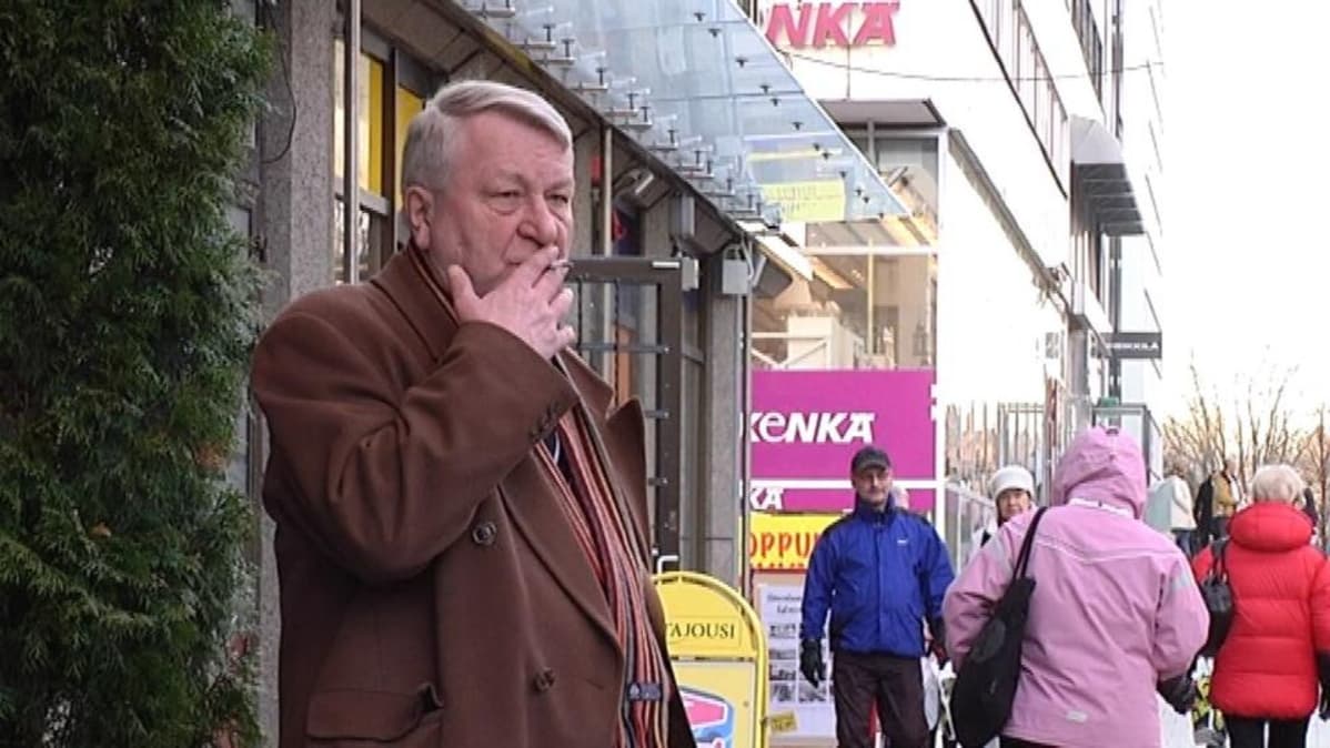 Mies seisoo kadulla ja polttaa tupakkaa.