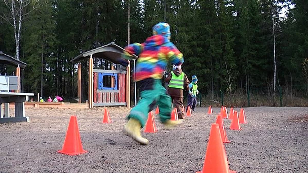 Lapset juoksevat kartioiden ympärillä päiväkodin pihalla