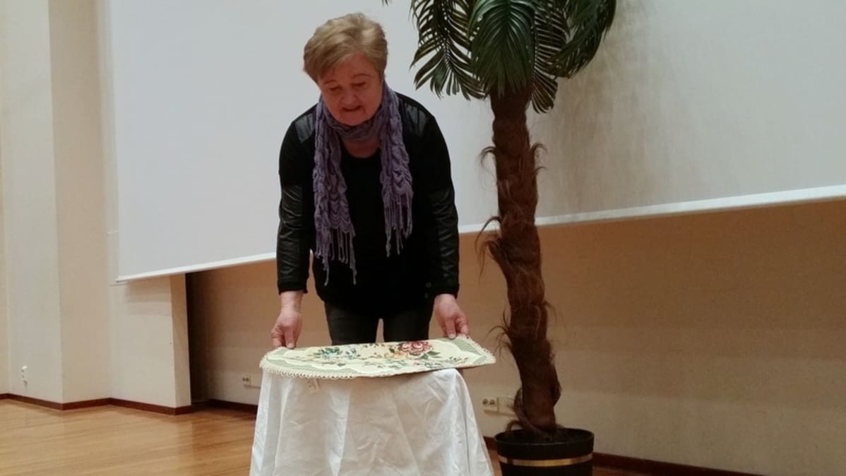 Sirkka Ravolainen asettelee lavasteita paikoilleen Kangasniemi-salissa.